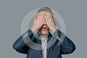 Man in jacket covering his face with palms