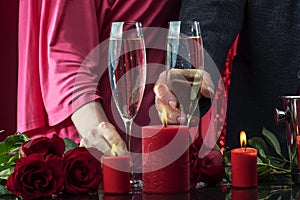 A man in a jacket and a woman in a pink dress are holding glasses of sparkling wine.