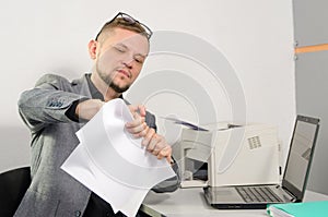 A man in a jacket is wrinkling documents in his hands at the off