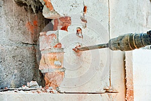 A man with a jackhammer makes an opening in the wall