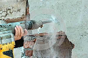 A man with a jackhammer makes an opening in the wall