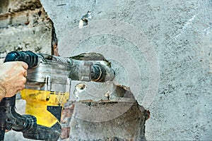 A man with a jackhammer makes an opening in the wall