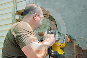 A man with a jackhammer makes an opening in the wall