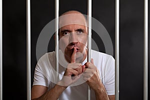 Man in jail gesturing to keep silence