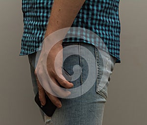 A man in jeans holding a phone in his hand lowered.