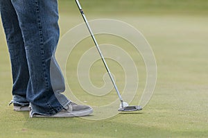 Man in jeans putting golf ball