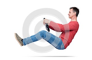 Man in jeans and red t-shirt drives a car with a steering wheel, isolated on white background. Auto driver concept