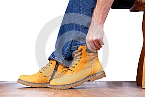 Man in jeans sits on chair and puts on nubuck winter boots