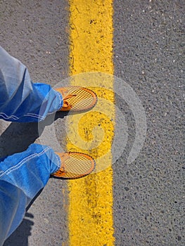 Man in jeans and a yellow shoes standing on the yellow band