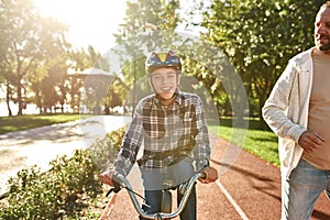 Man jog and boy with disability ride bicycle