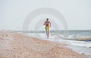 Man jogging on the desert sea line at the morning time