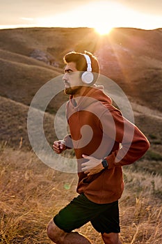 Man jogging on field. Guy runner running listening to music on smartphone