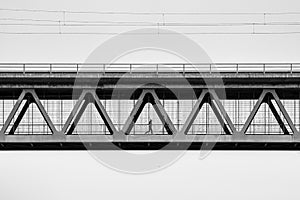 A man is jogging at the metal contrction of an iron bridge