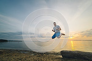 Man jump on the beach with sunrise on background