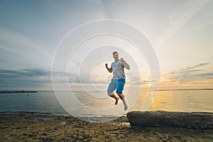 Man jump on the beach with sunrise on background