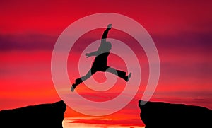 Man jump through the gap on sunset fiery background.