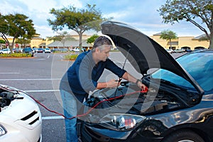 Man jump starting a car with jumper cables photo
