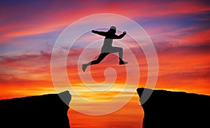 Man jumping across the gap from one rock to cling to the other.