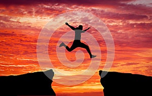 Man jumping across the gap from one rock to cling to the other.