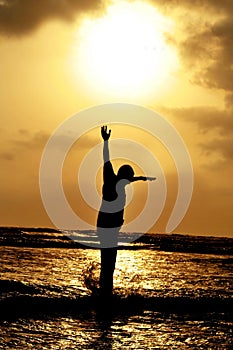 Man jumping against setting sun on beach