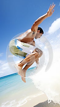 a man is jumping in the air at the beach while holding his arms up to