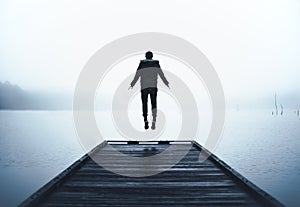 Man Jumping in Air Levitating at End of Wooden Dock Over Big Lake