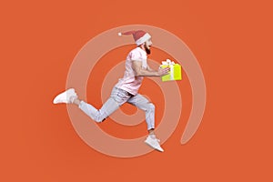 Man jumping in air or running quickly fast to give present box for Christmas, expressing happiness.