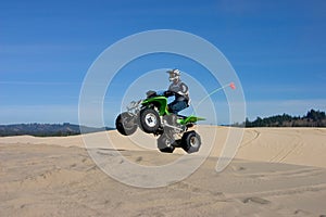 Man jumping ATV in sand dunes