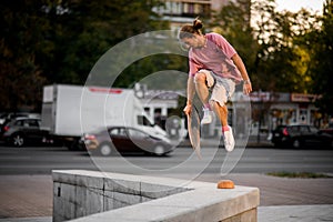 Man jumping with the balance board in hand on the concrete border in the town