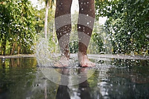 Man jumping with bare feet into puddle