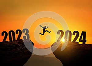 Man jumping on cliff 2024 over precipice at amazing sunset. New Year\'s concept.