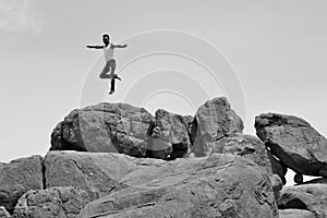 Man jumping or dansing on pile of rocks -B&W-