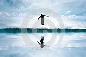 man jumping in the field and reflecting in the lake