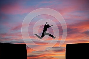 Man jumping a gap in sunset sky photo