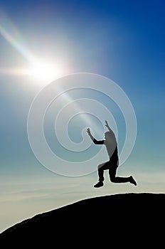 Man jumping on mountain peak silhouette