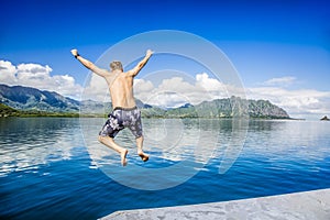 Man jumping into the ocean while on a beautiful scenic Hawaiian vacation