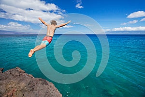 Man jumping off cliff into the ocean