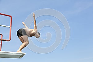 Man jumping off diving board at swimming pool