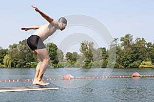 Man jumping off diving board at swimming pool