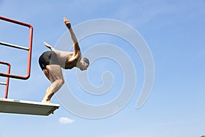 Man jumping off diving board at swimming pool