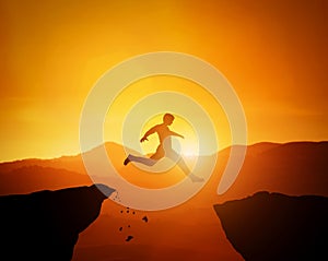 Man jumping from one rock to another. Sunset mountains scenery