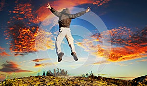 Man jumping out of happiness and emotions in front of a dramatic cloudy sunset