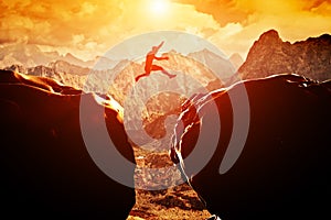 Man jumping over precipice between two mountains