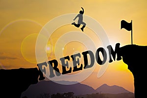 A man are jumping over to cliff and jump across freedom word.