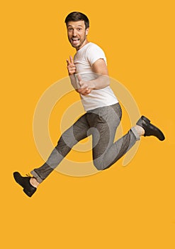 Man Jumping Pointing Fingers At Camera, Yellow Background