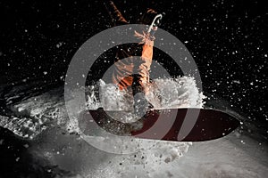 Man jumping with the snowboard in the mountain resort in the night