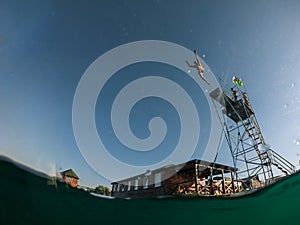 man jumping from tower to lake water