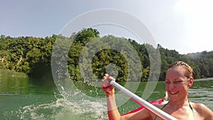 Man jumping into water from canoe while his girlfriend laughing in a canoe