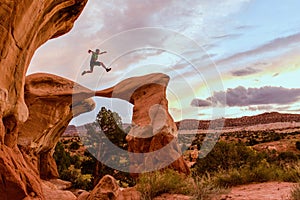 A Man Jumps Across a Curved Arch in Escalante