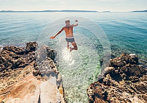 Man jumps in blue sea lagune water